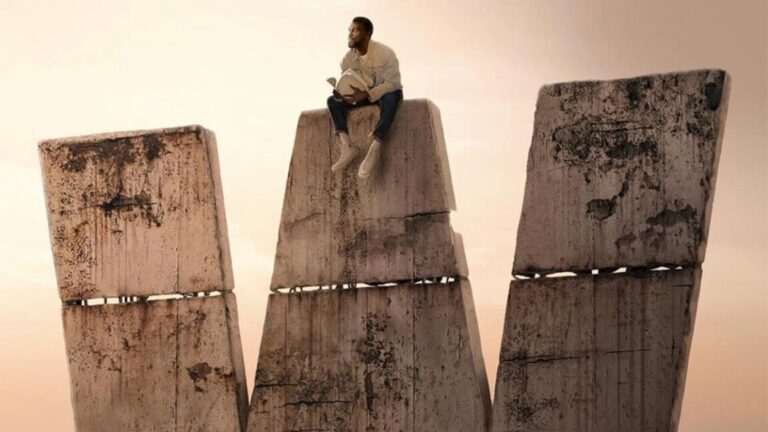 man sitting on top of a giant stone W