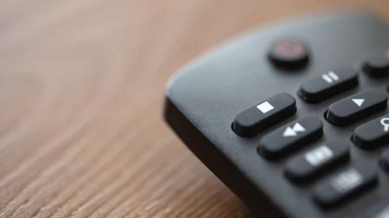 A detailed close-up stock photo of a smart TV remote placed on a wooden table.