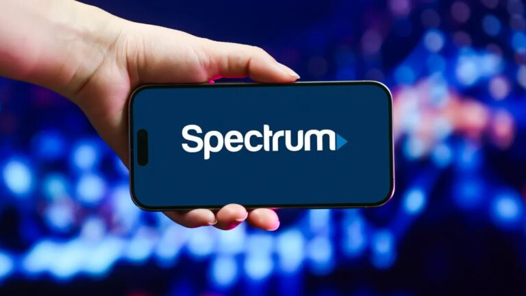 Spectrum logo on a phone being held by a hand.